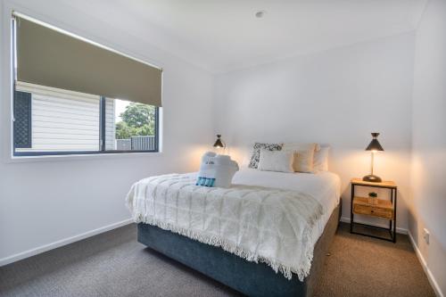 a white bedroom with a bed and a window at Tasman Holiday Parks - Fraser Coast in Hervey Bay