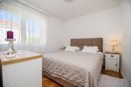 a white bedroom with a bed and a window at Apartment Dubravka in Povljana
