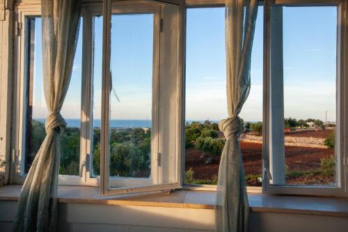 ein Fenster mit Vorhängen in einem Zimmer mit Aussicht in der Unterkunft Dimora Sanna Nature & Sea View in Polignano a Mare