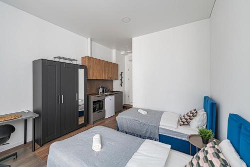ein kleines Zimmer mit 2 Betten und einer Küche in der Unterkunft Minimalist Studio Apartments by Hostlovers in Kaunas
