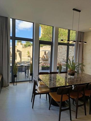 - une salle à manger avec une table, des chaises et des fenêtres dans l'établissement Villa Vera with private pool near Valletta, à Tal-Pietà
