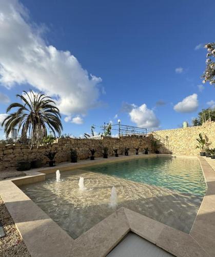 a swimming pool with a fountain in front of a stone wall at Villa Vera with private pool near Valletta in Tal-Pietà