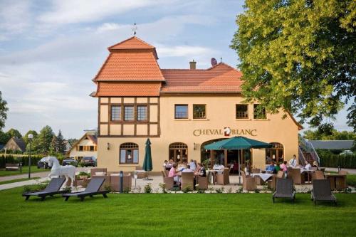 a building with people sitting at tables in front of it at Bernsteinschloss in Wendorf