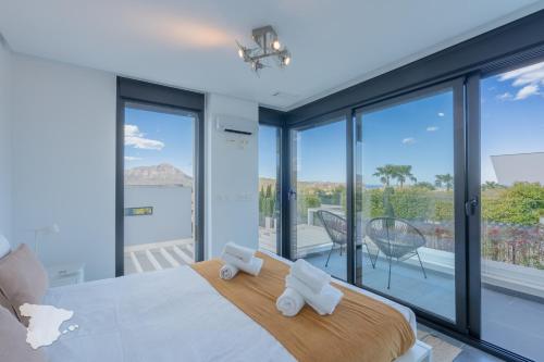- une chambre avec un grand lit et des parois en verre dans l'établissement CostaBlancaDreams Villa Strelitzia in Javea, à Benitachell
