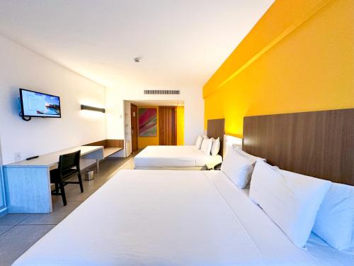 um quarto de hotel com duas camas e uma secretária em Enotel Porto de Galinhas All Inclusive em Porto de Galinhas