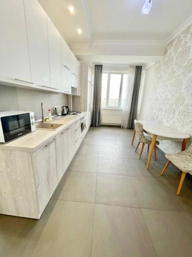 una cucina con armadi bianchi, tavolo e sedie di SKY apartament Amazing location a Chişinău