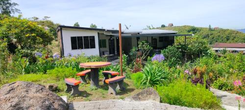 a garden with a table and benches in front of a house at KOMOWANAN HOMESTAY in Kundasang