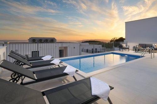 a swimming pool with lounge chairs next to a building at Ferienhaus Komplex - Villa David - Makarska Exklusiv in Veliko Brdo