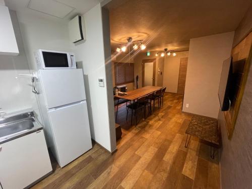 a kitchen and dining room with a white refrigerator and a table at Sofil 函館First in Hakodate