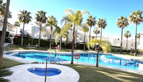 een zwembad met palmbomen voor een gebouw bij STYLISH TOWNHOUSE IN BEACHFRONT COMPLEX in Marbella