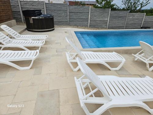 a group of white lounge chairs next to a swimming pool at Wild A-frame in Baile Felix