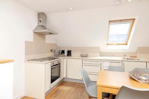 a kitchen with white cabinets and a table with chairs at JOIVY Superb Flats in the Heart of Edinburgh in Edinburgh