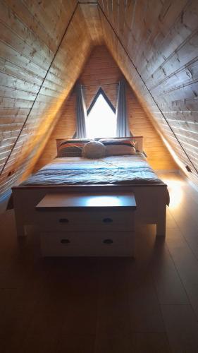 a bed with a window in a wooden house at Wild A-frame in Baile Felix