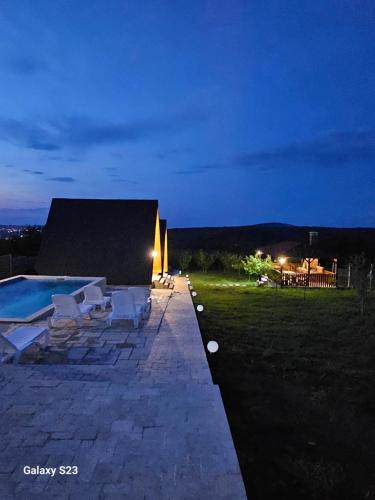 a patio with chairs and a swimming pool at night at Wild A-frame in Baile Felix