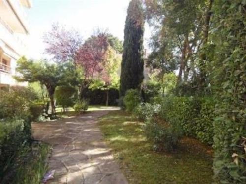 un chemin dans un jardin planté d'arbres et de buissons dans l'établissement Studio lumineux proche centre-ville de Montpellier, à Montpellier