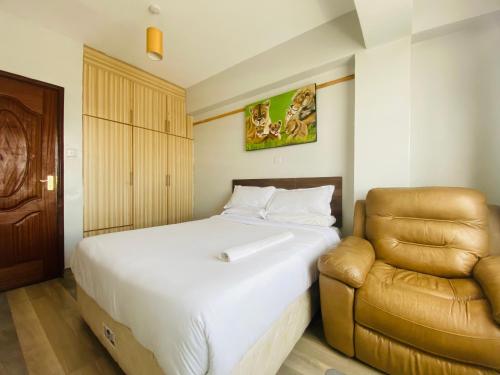 een slaapkamer met een bed en een stoel bij Pendeza Hyrax Residence in Nakuru