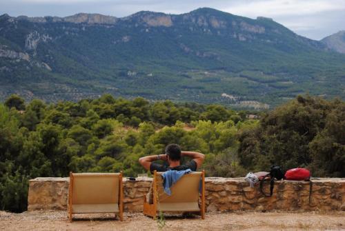 a man sitting on a rock wall looking at the mountains at Masia Villa Pilar Valderrobres in Valderrobres
