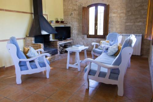 sala de estar con 3 sillas y chimenea en Masia Villa Pilar Valderrobres en Valderrobres
