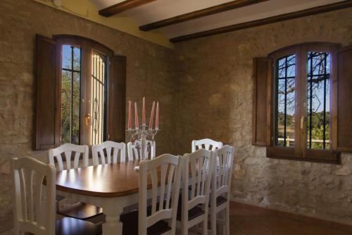 comedor con mesa de madera y sillas blancas en Masia Villa Pilar Valderrobres, en Valderrobres