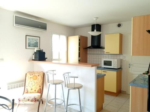 une cuisine avec un comptoir et des tabourets dans une pièce dans l'établissement La maison aux volets rouges, à Saint-Hilaire-de-Riez