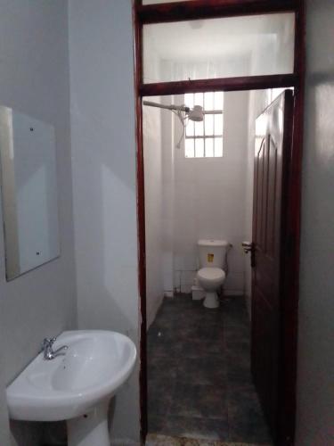 La salle de bains est pourvue de toilettes blanches et d'un lavabo. dans l'établissement Peace Haven, à Kamondo