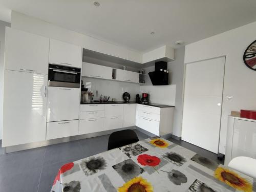 - une cuisine avec des placards blancs et une table fleurie dans l'établissement La moderna de la Pège, à Saint-Hilaire-de-Riez