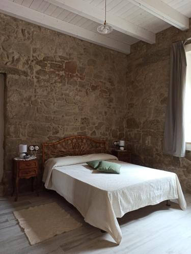 1 dormitorio con cama y pared de piedra en Piazza San Giorgio, en Dolianova