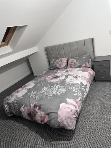 ein Schlafzimmer mit einem Bett mit rosa Blumen drauf in der Unterkunft Rarri place in Manchester