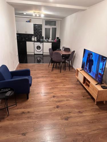 ein Wohnzimmer mit einem blauen Sofa und einem TV in der Unterkunft Rarri place in Manchester