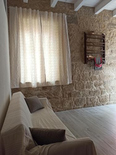 a bedroom with a bed and a window with a curtain at Piazza San Giorgio in Dolianova