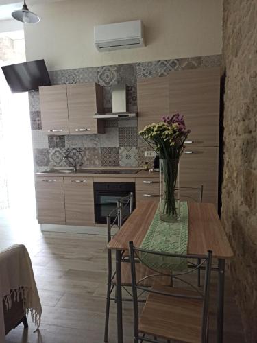 a kitchen with a table with a vase of flowers on it at Piazza San Giorgio in Dolianova