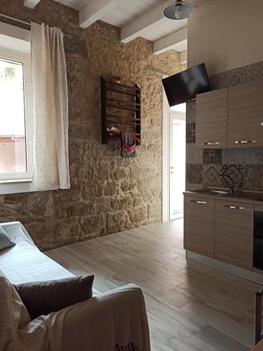 1 dormitorio con paredes de piedra, 1 cama y TV en Piazza San Giorgio, en Dolianova
