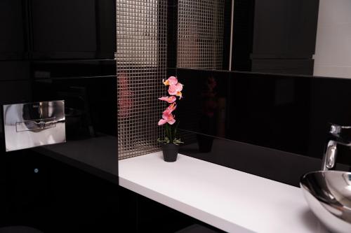 une fleur rose assise sur un comptoir dans une salle de bains dans l'établissement Siedlisko Staszkówka, 