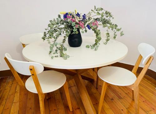 een witte tafel met twee stoelen en een vaas met bloemen bij La Casa de María Pita in A Coruña