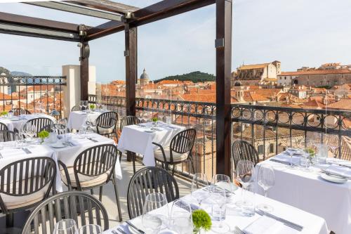 um restaurante com mesas brancas e cadeiras numa varanda em Boutique Hotel Stari Grad em Dubrovnik