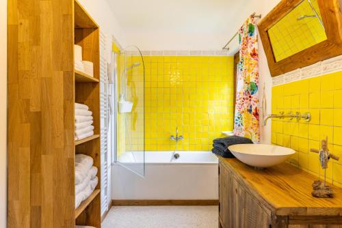 uma casa de banho com um lavatório, uma banheira e azulejos amarelos em Kiwi Retreat em Bad Urach