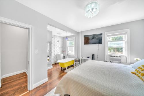 a white bedroom with a bed and a yellow chair at 3 bedroom in Brooklyn