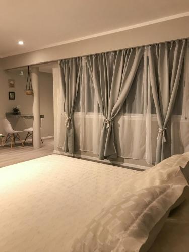 1 dormitorio con 1 cama grande y cortinas en Confortabile Apart en San Fernando del Valle de Catamarca