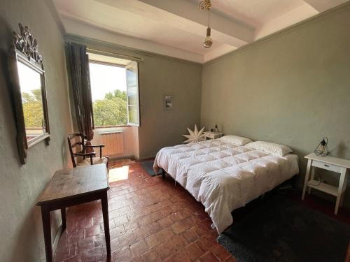 ein Schlafzimmer mit einem Bett, einem Tisch und zwei Fenstern in der Unterkunft Magnifique maison Le Barroux in Le Barroux