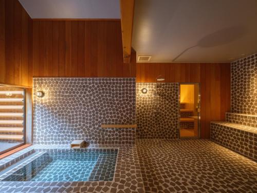 ein Bad mit einer Badewanne und einer Dusche mit Fliesen in der Unterkunft Kameya Hotel in Tsuruoka