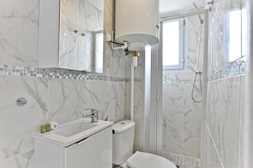 une salle de bain blanche avec des toilettes et un lavabo dans l'établissement Appartement paisible en banlieue parisienne, à Gagny