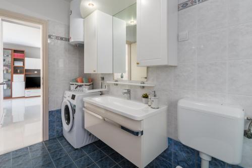 een witte badkamer met een wastafel en een wasmachine bij Apartment Sara Premium in Funtana