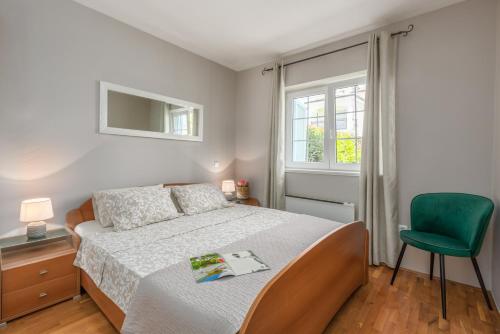 een slaapkamer met een bed en een groene stoel bij Apartment Sara Premium in Funtana