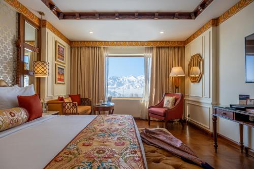 a bedroom with a bed and a desk and a window at The Grand Dragon Ladakh in Leh