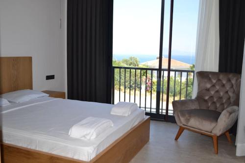 ein Schlafzimmer mit einem Bett und einem Stuhl sowie einem Balkon in der Unterkunft çeşme boyalıkta süper lüks in Cesme