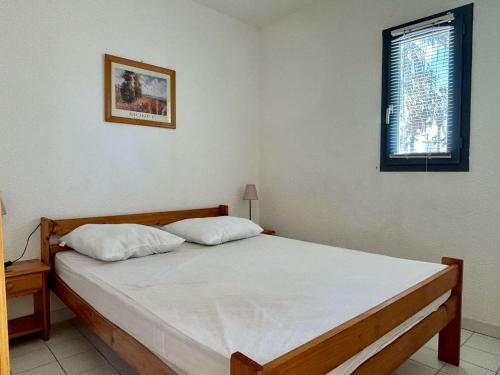 - une chambre dotée d'un grand lit avec des draps blancs et une fenêtre dans l'établissement Appartement 2 pièces avec terrasse et parking à 150m de la mer - FR-1-225-451, à Argelès-sur-Mer