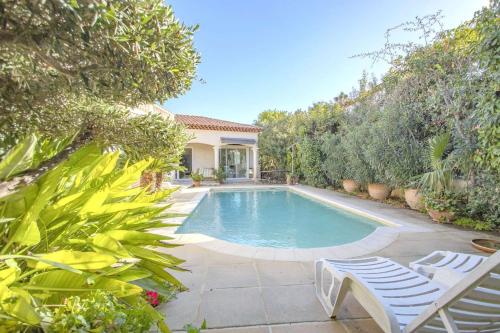 une piscine avec deux chaises et une maison dans l'établissement Villa Flora, à Carqueiranne