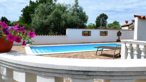 a pool in a backyard with a white fence and flowers at Apartments Villa Ksenija in Umag