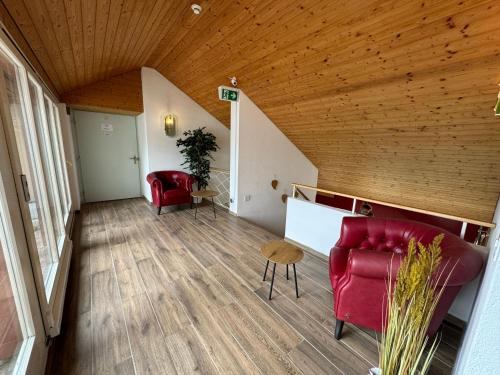 uma sala de estar com mobiliário vermelho e um tecto de madeira em Lake View Double Room em Därligen