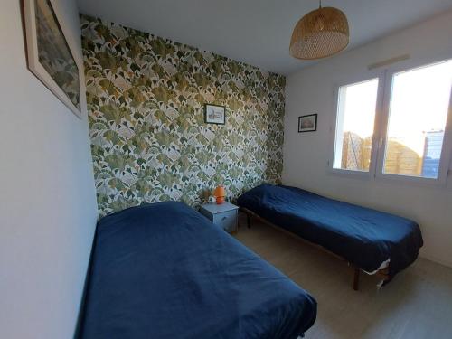 - une chambre avec 2 lits et un mur orné de fleurs dans l'établissement L'Oberlin de la ville, à Saint-Hilaire-de-Riez